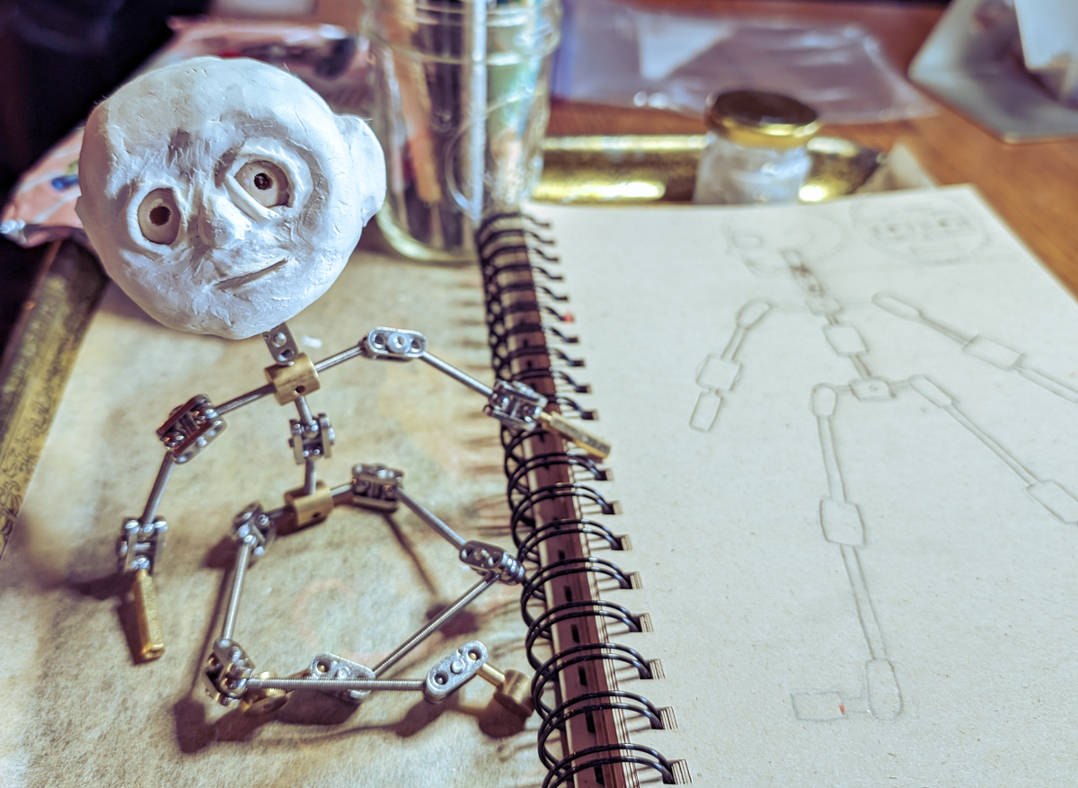 Head added to armature, seated next to a sketch